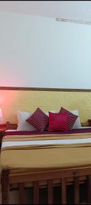 a bed with red and white pillows on it at Ocean Pearl Resort in Varkala +3 photos