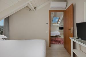 a bedroom with a white bed and a television at Anemolia Resort and Spa in Ioannina