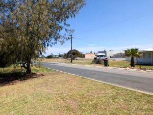 an empty road with trees on the side of the road at Aqua Sands Chalets in Lancelin