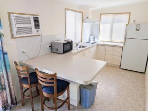 a kitchen with a white table and chairs and a refrigerator at Aqua Sands Chalets in Lancelin