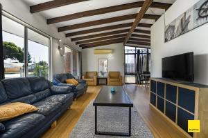 a living room with a black leather couch and a tv at Sea Gem in Lancelin