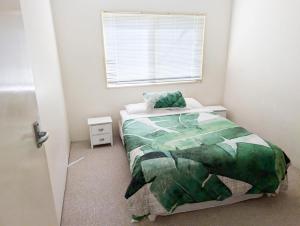 a bedroom with a bed with a green comforter and a window at Aqua Sands Chalets in Lancelin