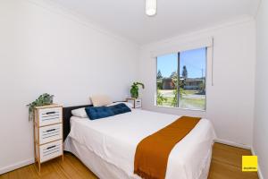 a white bedroom with a bed and a window at Sea Gem in Lancelin