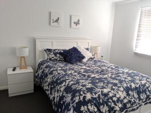 a bedroom with a bed with a blue and white comforter at Seagulls in Lancelin
