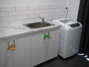 a white kitchen with a sink and a trash can at Seagulls in Lancelin