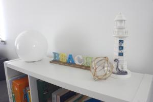 a shelf with a white table with books and a lighthouse at Seagulls in Lancelin