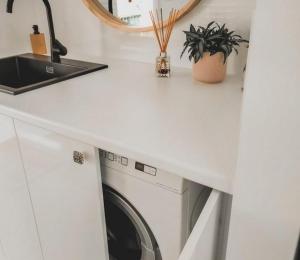 a laundry room with a washing machine under a counter at Sou Wester in Lancelin +10 photos