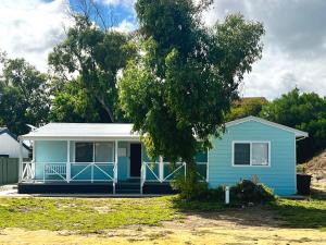 a blue house with a tree in front of it at Playgrounds in Lancelin