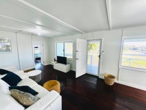 a living room with a white couch and a tv at Playgrounds in Lancelin