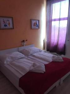 Un dormitorio con una gran cama blanca con ventana. en Y Panzió Party Rooms, en Balatonlelle