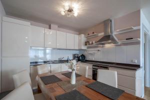 Una cocina con una mesa de madera y gabinetes blancos. en Penthaus Schlossbühl, en Oberuhldingen 2 fotos más