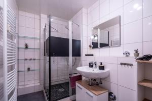 Un baño blanco con lavabo y ducha. en Penthaus Schlossbühl, en Oberuhldingen