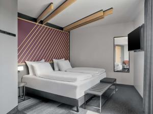 a bedroom with a white bed and a mirror at B&B HOTEL Bielefeld-City in Bielefeld
