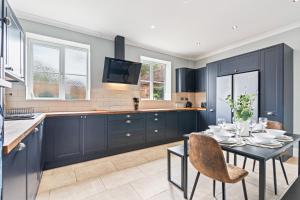 a kitchen with blue cabinets and a table and chairs at Stunning and Charming 4-bed Home in Newark by Renzo, Free Wi-Fi, Sleeps 8! in Tuxford +28 photos