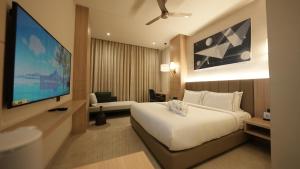 ein Hotelzimmer mit einem Bett und einem Flachbildfernseher in der Unterkunft Pride Elite Raipur in Raipur