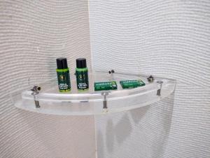a glass shelf on a wall with two bottles ofodorizers at PIITAMBARA HOMES LUXURY Stay in Faizābād