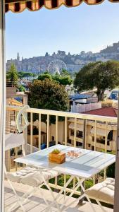 a white table on a balcony with a view of a city at MENTON BORD DE MER Studio calme avec balcon, Ascenseur, Climatisation, Ideal location quiet near sea, balcony, elevator, AC in Menton