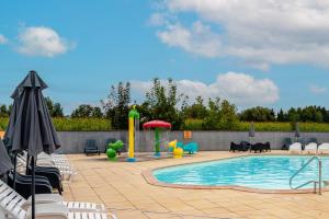 a swimming pool with a fountain and chairs and an umbrella at Lydia's Mobilhome am Europa-Park in Boofzheim
