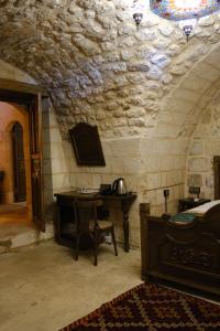 a bedroom with a bed and a table in a stone room at Badgirli Konak in Urfa