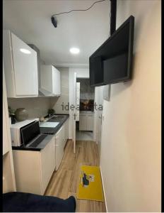 een keuken met witte kasten en een flatscreen-tv aan de muur bij Casa Duque in Madrid