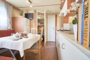 eine Küche mit einem Tisch mit einer weißen Tischdecke in der Unterkunft Feriendorf Oasi Mobilehome Tahiti für 4 Personen in Sottomarina