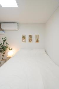 a white bedroom with three pictures on the wall at Hanook jongno in Samgong