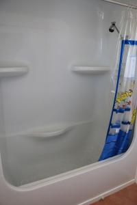 una vasca da bagno bianca con una tenda da doccia blu di Sea'Renity Cottage a Venus Bay