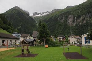 une aire de jeux dans un village avec des montagnes en arrière-plan dans l'établissement Haus Steiner, à Göschenen