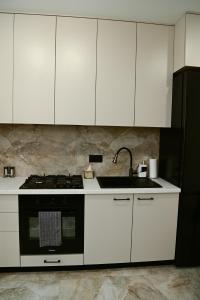 a kitchen with white cabinets and a sink and a stove at Яровиця 9 новобуд in Lutsk