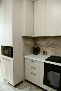a kitchen with white cabinets and a stove at Яровиця 9 новобуд in Lutsk +2 photos