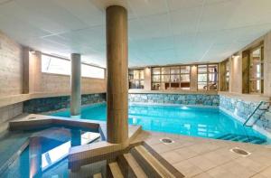 a large swimming pool with blue water in a building at Les Flanamolo's-Charming apartment luxury complex in Les Gets