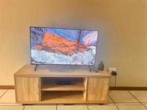 een flatscreen-tv op een houten standaard bij Eden Place in Vosburg