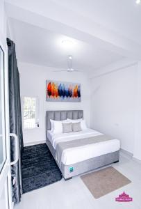 a white bedroom with a bed and a painting on the wall at Prabhaz Grand in Hatton