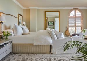 a bedroom with a white bed and two white chairs at Villa del Mar - "Luxurious en-suite bedroom with lounge and stunning sea view balcony in Bantry Bay" in Cape Town
