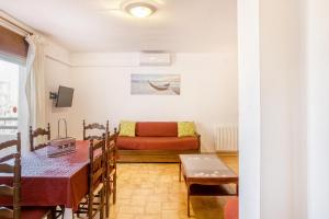 ein Wohnzimmer mit einem roten Sofa und einem Tisch in der Unterkunft Apart en Paseo Marítimo 2-3 in Llança + 14 Fotos