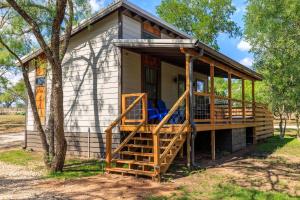 une petite maison avec une véranda et un arbre dans l'établissement Verbena Waterfront with Hot Tub, à Tivydale