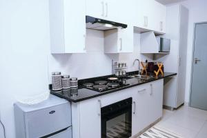 a kitchen with white cabinets and a stove top oven at Lanekwa's in Gaborone