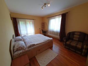 a bedroom with a bed and a couch and two windows at Cabana Muntele Paltinei in Muntele Rece