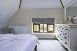 a white bedroom with a bed and a window at Ashdale Cottage in Christchurch +50 photos