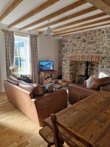 un soggiorno con divani e camino in pietra di Rustic Welsh cottage a Llanwrtyd Wells