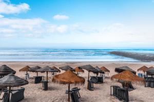 a beach with many straw umbrellas and the ocean at T2 na Caparica vista Praia in Costa da Caparica