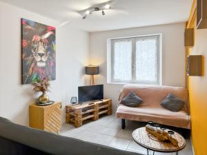 a living room with a couch and a tv at Logement de 40m2 de plein pieds dans une maison avec parking et terrasse in Jussac