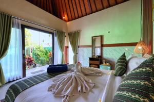 a bedroom with a large bed with a large window at WK Penida Cottage in Nusa Penida