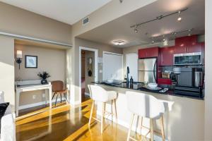 a kitchen with red cabinets and white bar stools at Summit Mountain & Skyline Views Beltline in Calgary