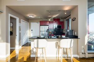 a kitchen with red cabinets and white bar stools at Summit Mountain & Skyline Views Beltline in Calgary
