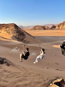 two people are playing on strings in the desert at Wadi Rum ZAAD luxury Camp in Wadi Rum