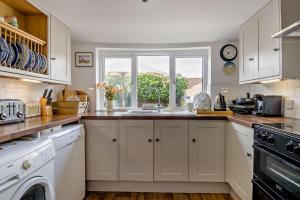 Una cocina con gabinetes blancos y una ventana. en Salty Dog, en Mundesley 7 fotos más