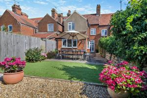 Un jardín con una mesa y una sombrilla delante de una casa. en Salty Dog, en Mundesley