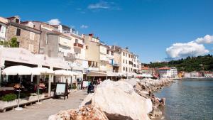 un groupe de bâtiments à côté d'une masse d'eau dans l'établissement Apartments & Rooms Riva, à Piran