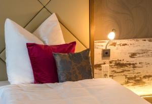 Una cama con almohadas rojas y blancas y una lámpara. en Hotel Allegro en Halberstadt